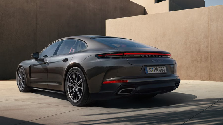 Black Porsche Panamera parked in front of a minimalist concrete building.