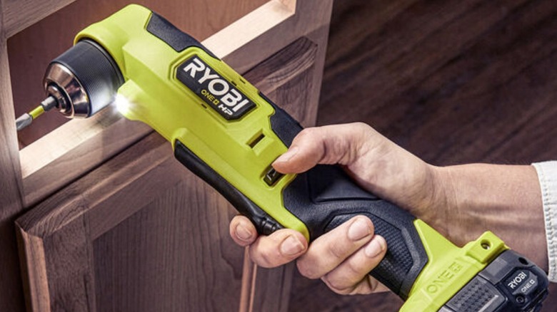 Person using Ryobi right angle drill on cabinet