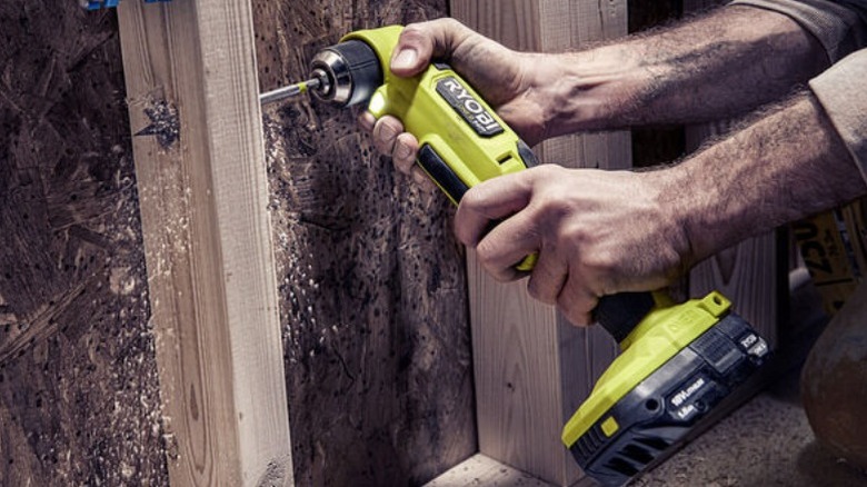 Person using Ryobi right angle drill on wall stud