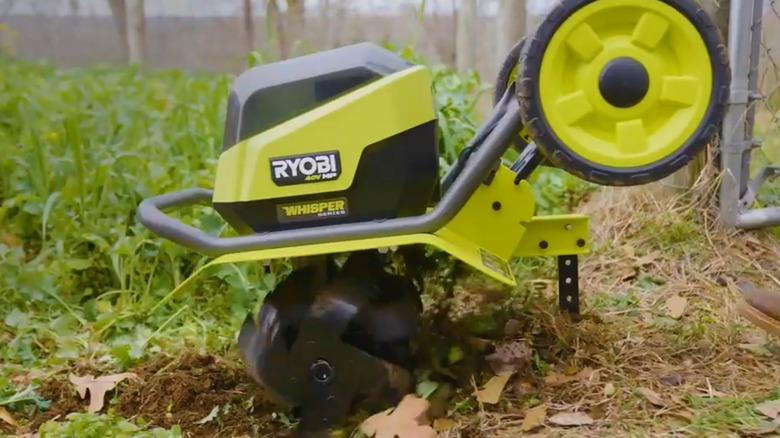 A person using Ryobi's front tine tiller on soil.