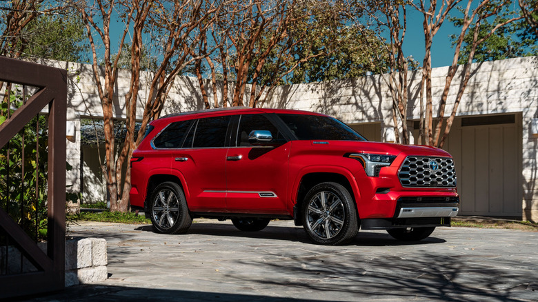 2025 Toyota Sequoia Capstone parked on a paved surface with a building in the background, red exterior, front 3/4 view
