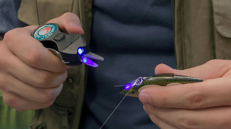 Close-up of someone using the Boomerang Tool Company Super SNIP Fishing Line Cutter with Glow Jig Charging U/V Light