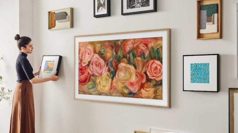 Woman hanging picture next to Samsung Frame TV