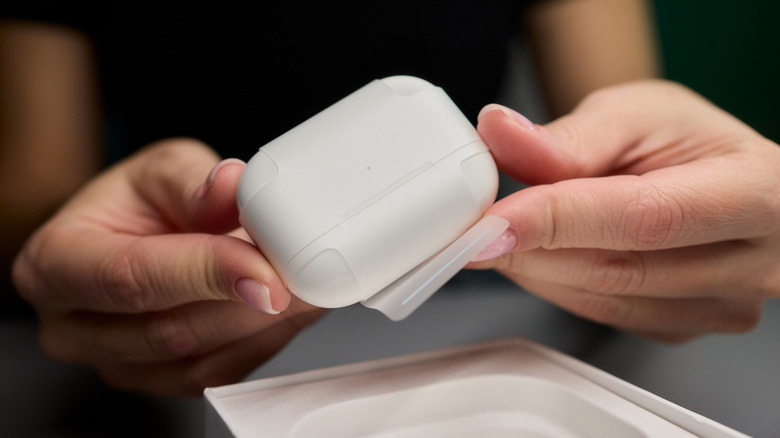 Hands holding a brand new AirPods charging case