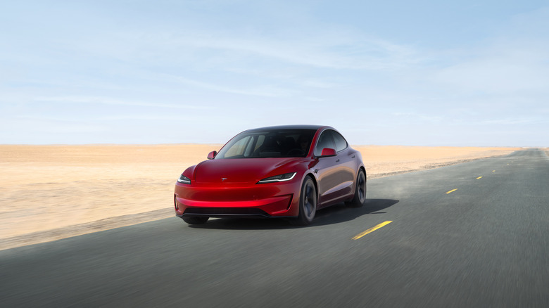 A red Highland Tesla Model 3 on the move on a desert road, front 3/4 view