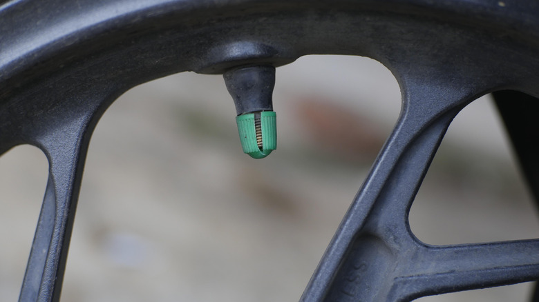 Close-up of a a motorcycle wheel's air valve with a green cap