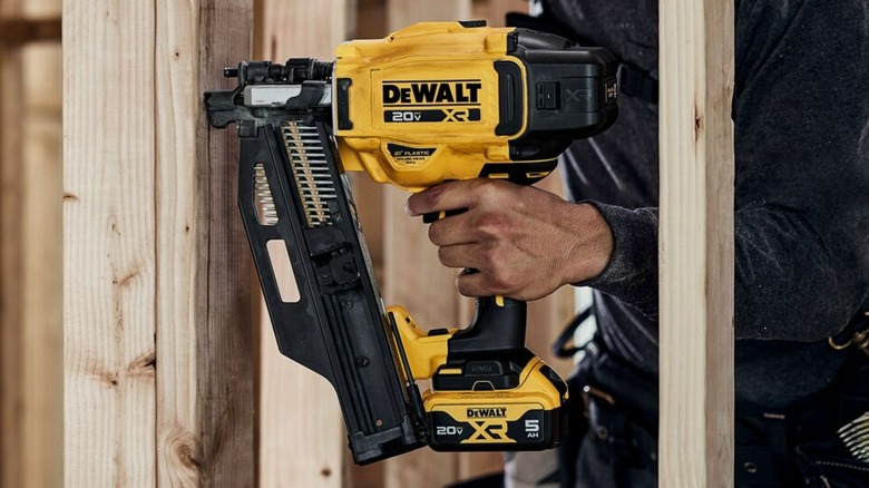 Hand presses trigger on DeWalt nail gun