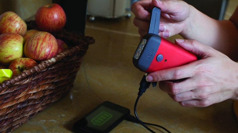 a person using the eton red cross crank tool to charge their phone