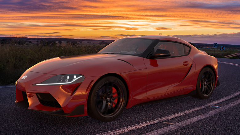 red toyota supra driving on road at sunset