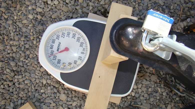 A trailer tongue weighing on an analog bathroom scale supported by wooden blocks