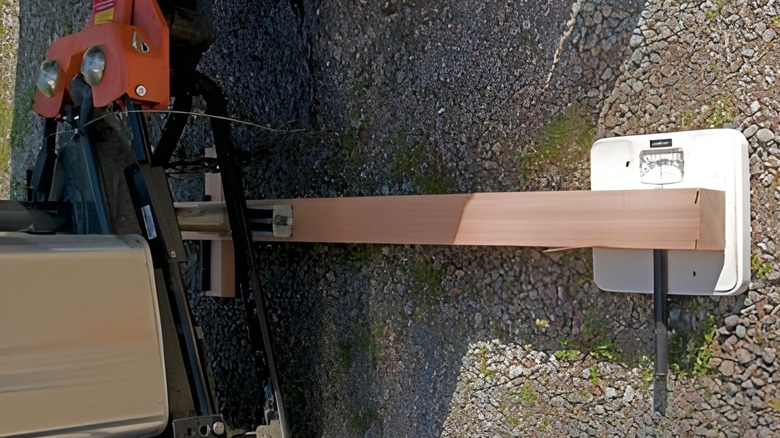 A wooden beam connected to a trailer's tongue weighing on a bathroom scale