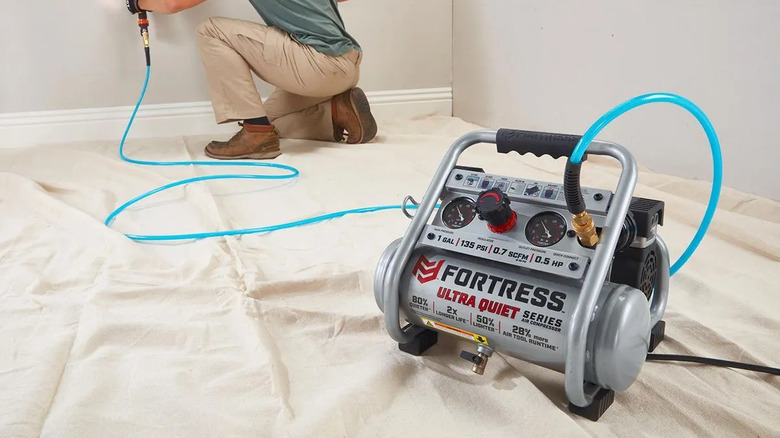 A Fortress one-gallon air compressor in use on a tarp.