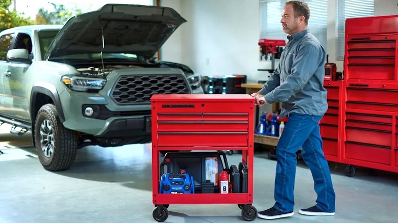 Person rolling a U.S. General tool box across a garage floor.
