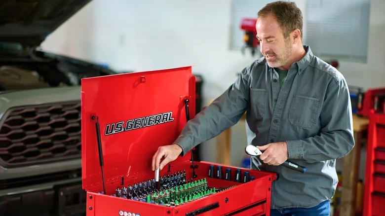 Person reach into an open U.S. General tool box to remove a tool.