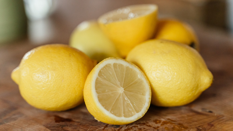 Whole and sliced lemons on a wooden table
