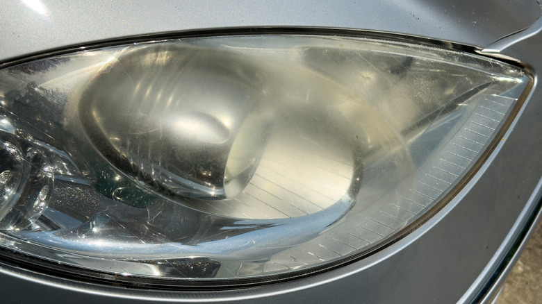 Close up of cloudy car headlight on silver vehicle