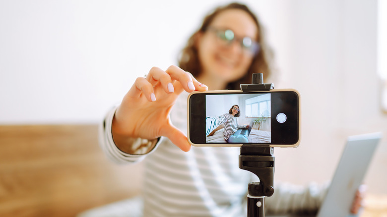 woman setting phone on tripod