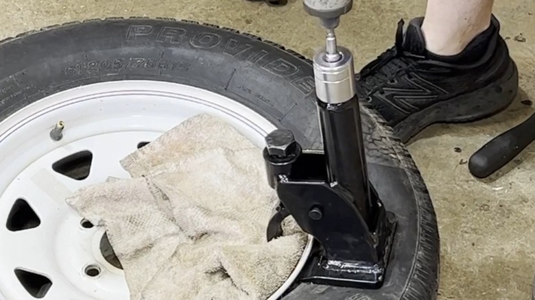 Using the Maddox manual bead breaker to loosen the tire bead from a wheel.