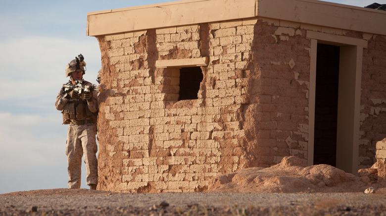 Soldier takes cover behind a building during training exercise.