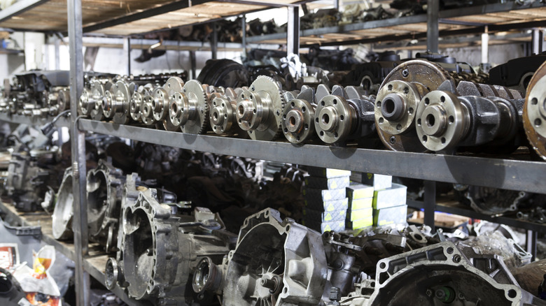 Close up view of used auto parts and transmissions being stored on rack.