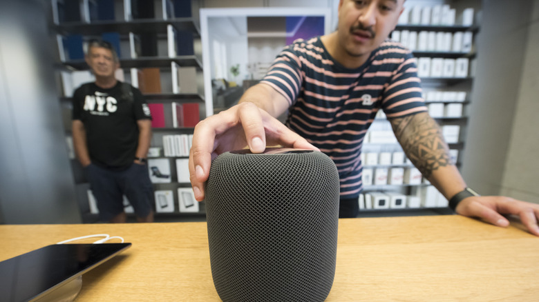 Person tapping on the top of a HomePod speaker.