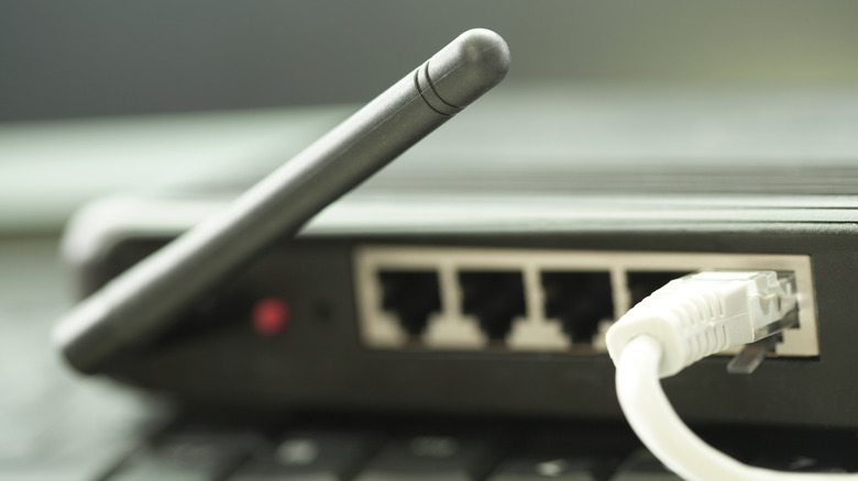 Router placed on a keyboard with a white Ethernet cable connected to one of the LAN ports