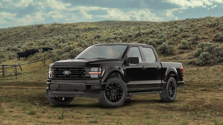 A black 2026 Ford F-150 sitting on dirty with a fence, hills and cattle behind it