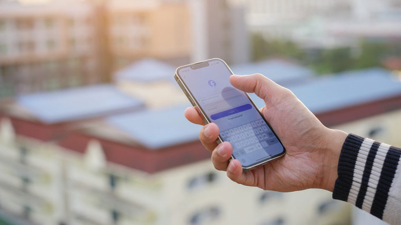 A person using an iPhone that's displaying the Facebook login page.