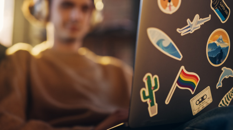 Person using a laptop with stickers on the lid
