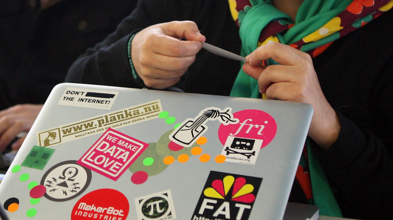 A person putting a sticker on their laptop