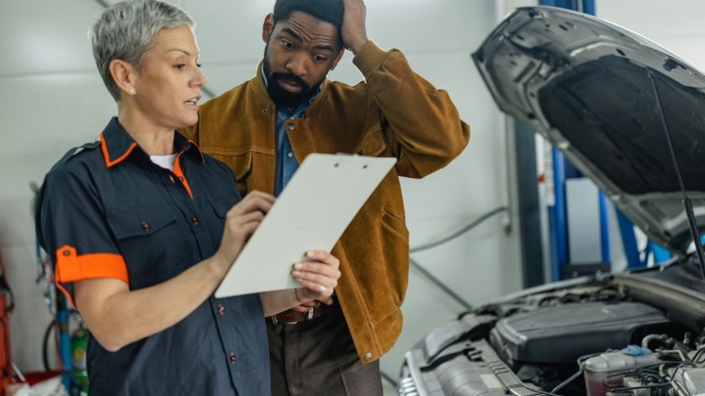 a mechanic showing a customer their repair order and explaining why the repairs are necessary