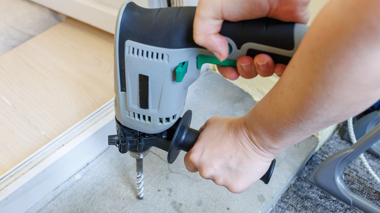 Drilling a hole in a concrete floor surface with a professional hammer drill tool