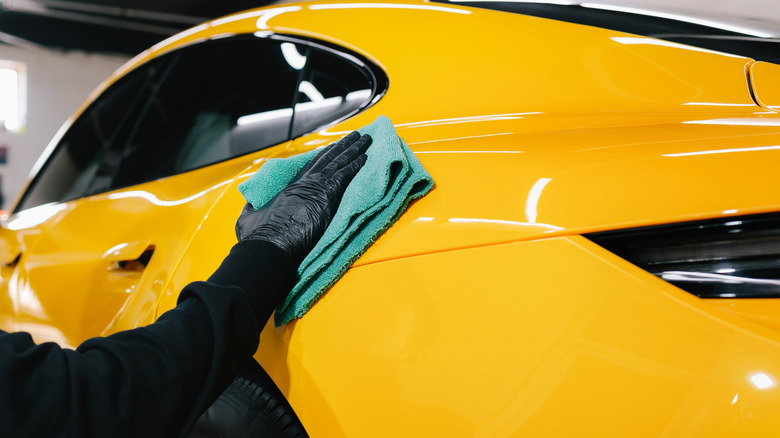 Person cleaning a car with a microfiber cloth