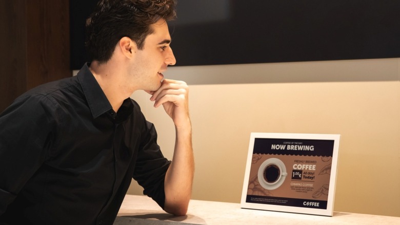 A person sitting and looking at a Samsung Color E-Paper.