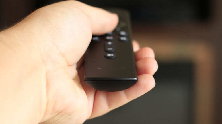 Person pointing Amazon Fire TV remote at TV
