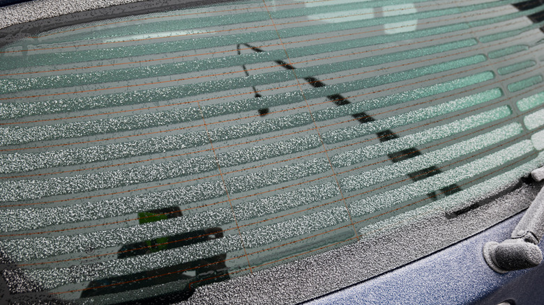 A snowy car rear window being defrosted