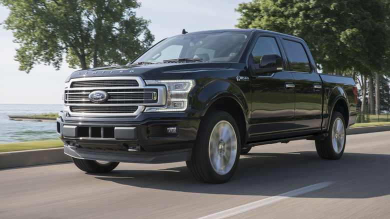 Black 2019 Ford F-150 driving on a coastal road.