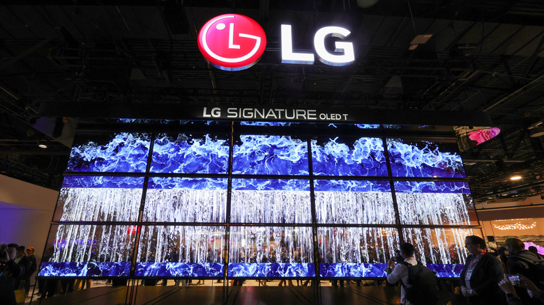 A number of LG OLED TVs arranged in a display to show a cascade of water beneath a massive LG logo and the text "LG Signature OLED T"
