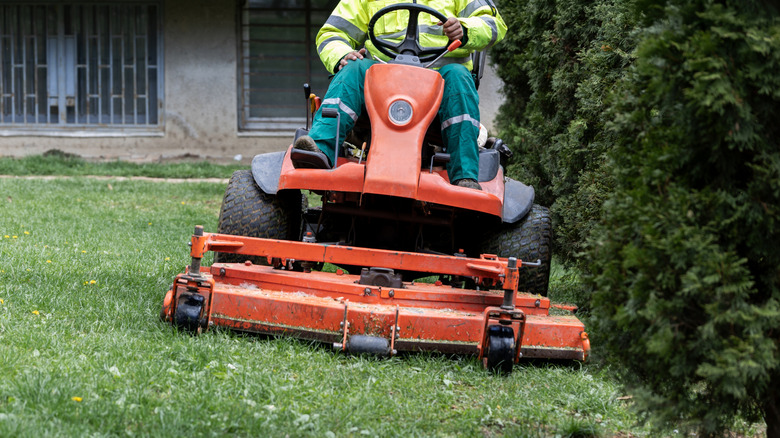 A person cutting grass with a riding lawn mower.