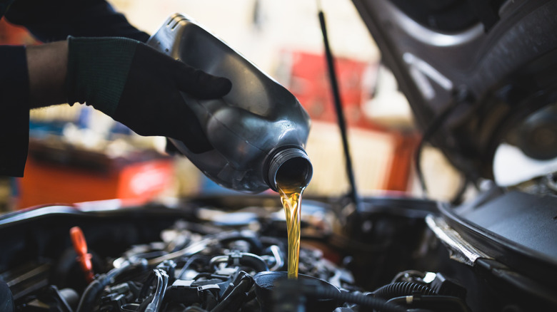 A close-up of a man putting oil into his car engine