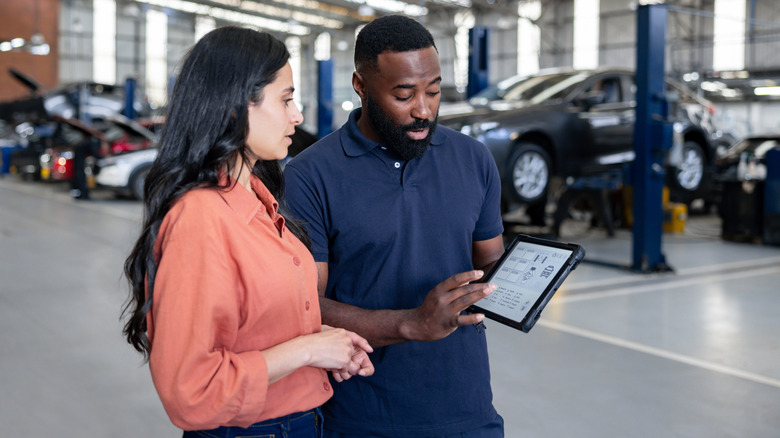 An unhappy woman talks to a mechanic about work done to her car