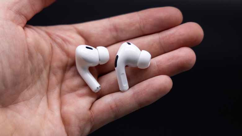 Hands holding pair of AirPods