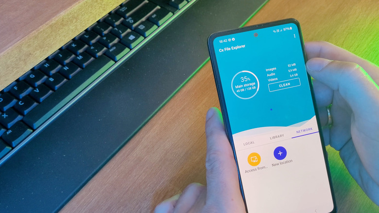 An Android device running Cx File Explorer, wooden desk and keyboard in the background, green ambient lighting