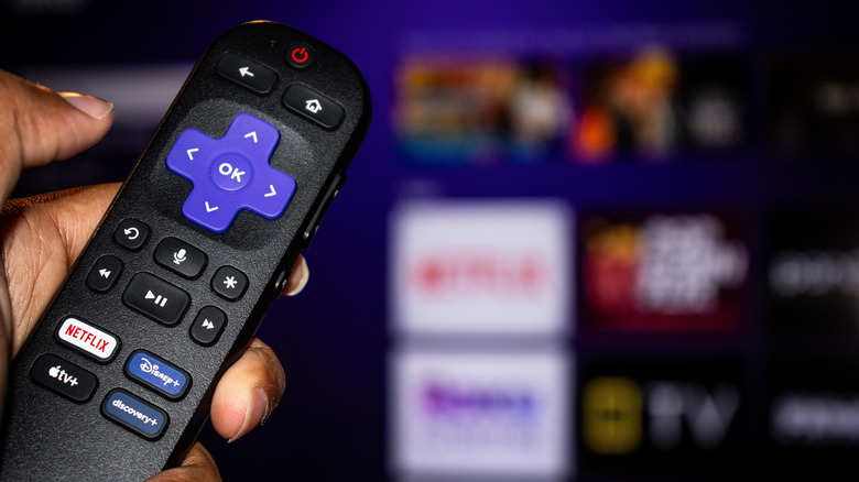 Person using a Roku TV remote control