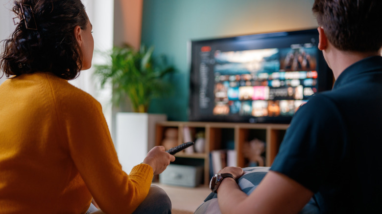 People sitting in front of a smart TV with the screen on and remote in hand