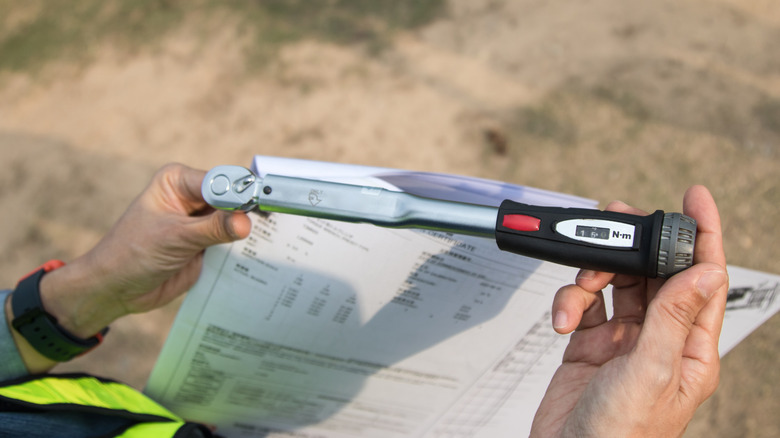 Hands holding a torque wrench over a user manual.
