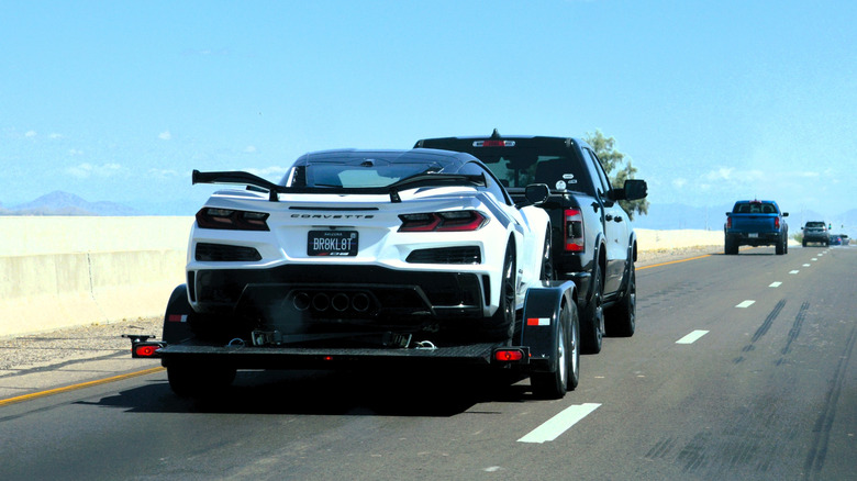 A corvette being towed by a pickup truck