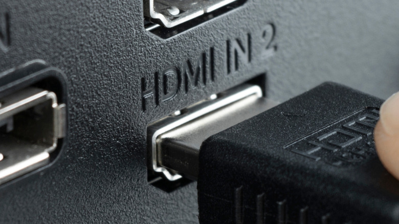 A person plugging an HDMI cable into an HDMI port.