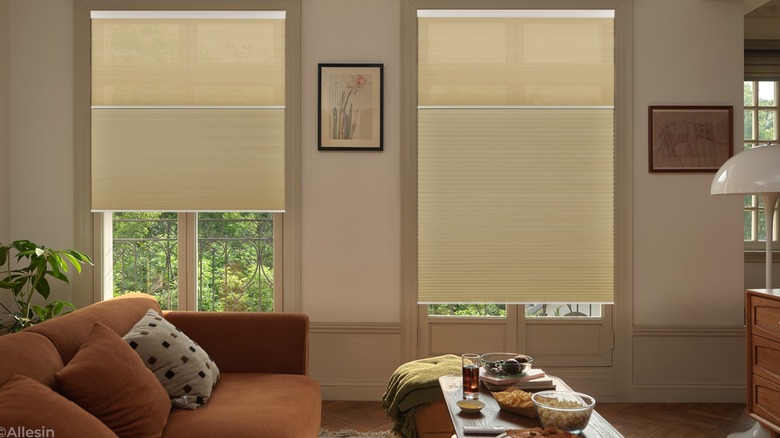 Smart shades on two windows in living room with orange couch