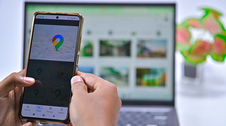 Hands holding a smartphone with a location point in Google's colors